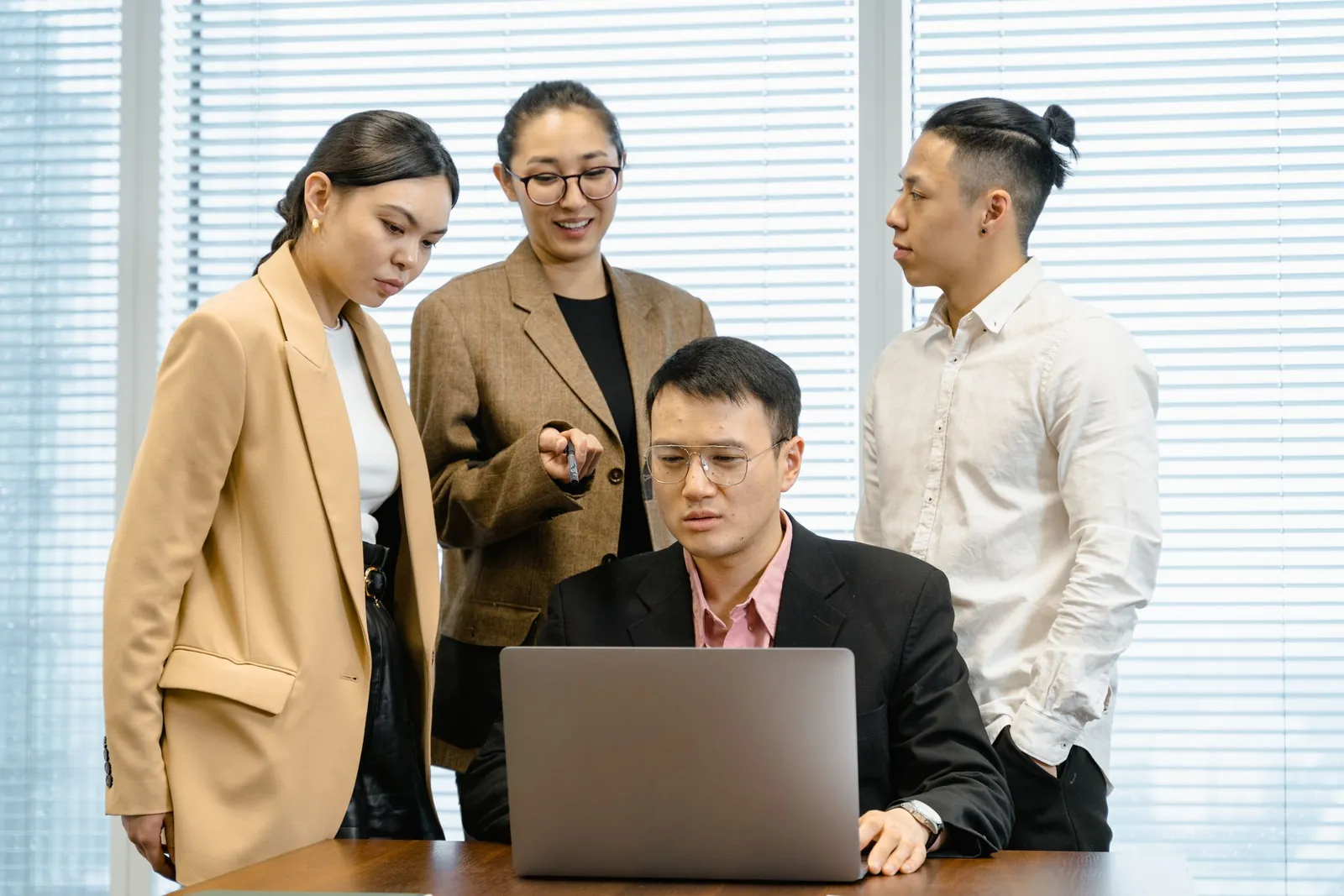 会議室でノートパソコンの画面を指しながら、同席するチームのメンバーに候補者の選考状況を伝える採用担当者