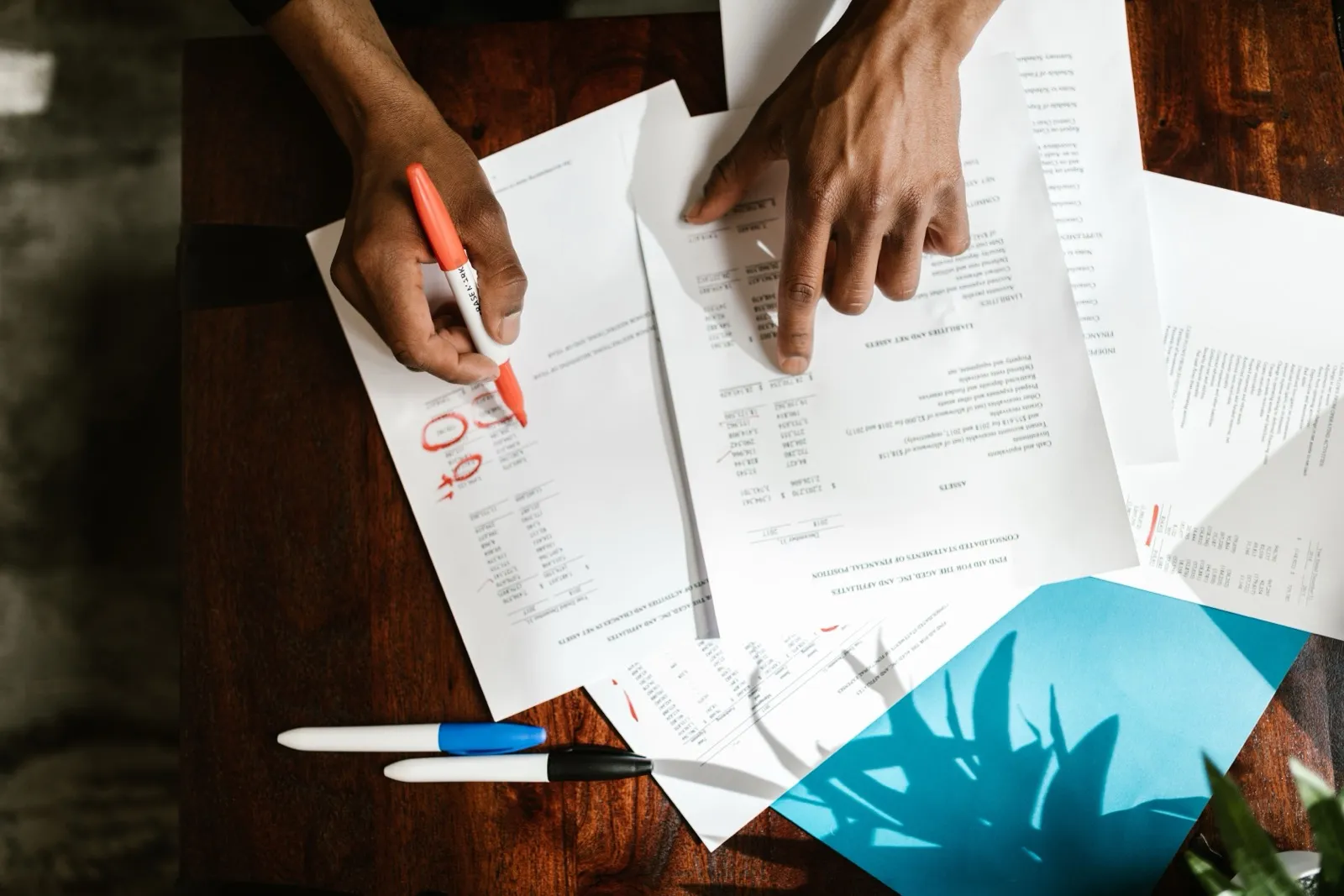 会議室で3社分の提案書を机に並べて見比べている企業の採用担当者の手元