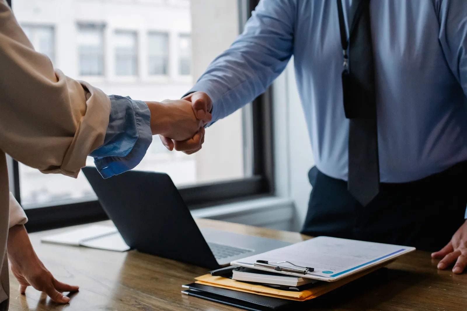 オフィスのデスクで、印刷した求人票を前に人材紹介会社の担当者と向かい合って打ち合わせをしている企業の採用担当者