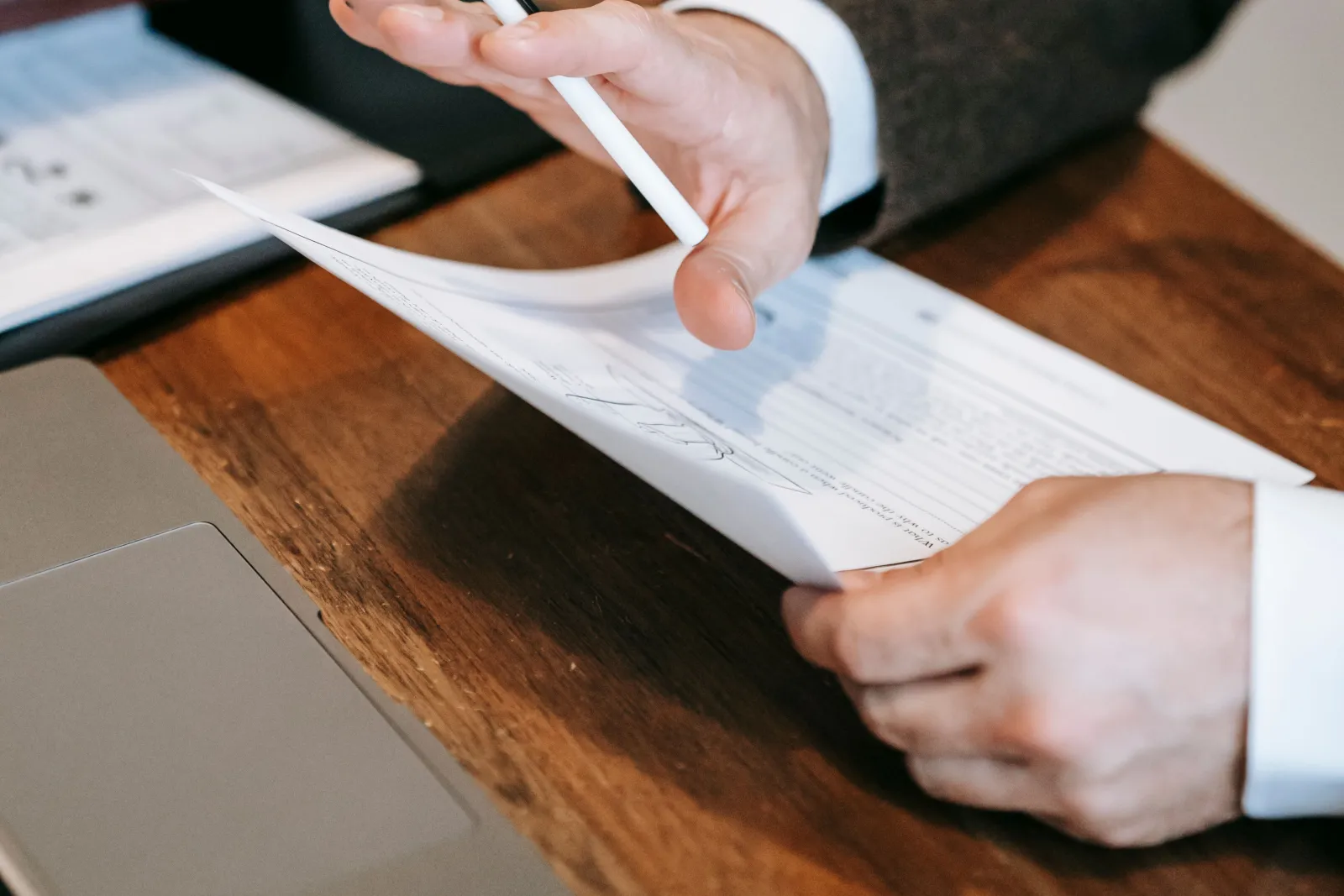 オフィスのデスクで契約書の条項を指でたどりながら読み込んでいる採用担当者の手元