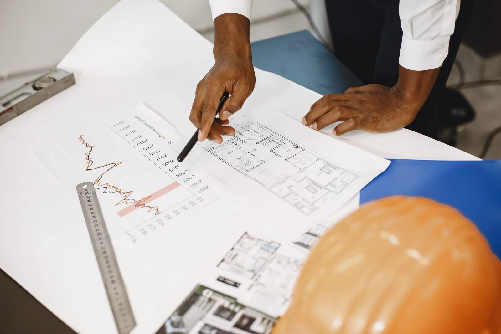 オフィスのデスクに建設工事の図面と求人書類が並び、採用担当者が資料を見比べている様子
